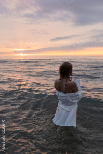 Back view of a woman in the ocean at sunset