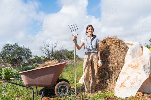 Εκτύπωση καμβά Woman smiling holding pitchfork on outdoor permaculture farm