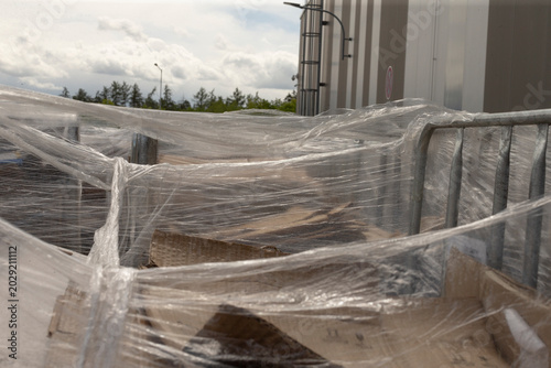Pallets wrapped awaiting truck, outbound staging at loading dock with metal railing and concrete wall, corrugated boxes ready for forklift pickup and dispatch
