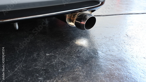 Cuadro en lienzo Close up of a polished stainless steel car exhaust tip on a black garage floor