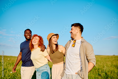 Fotografie Group of diverse young friends enjoying a cheerful walk together, embracing frie