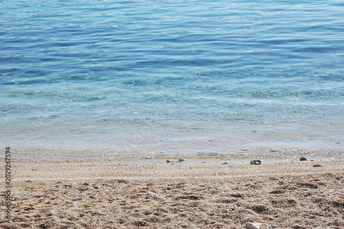 Foto Scenic view of small waves lapping onto a smooth pebble beach with clear blue sea water
