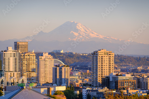 The urban skyline of Seattle, USA, with the backdrop of Mount Rainier's snow-capped peaks.