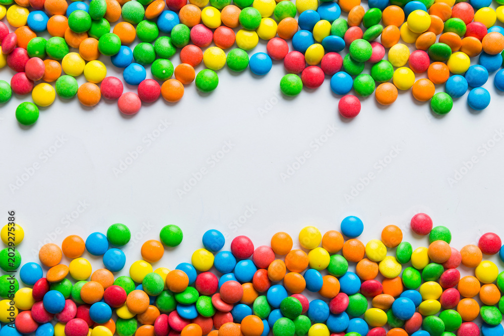 Obraz premium Mixed collection of colorful candy, on colored background. Flat lay, top view. frame of colorful chocolate coated candy