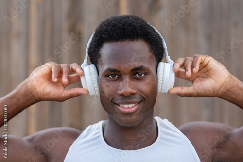Close up portrait of smiling young African athlete wearing headphones during workout