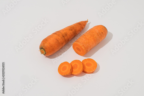 Fresh organic raw carrots, whole, half, and sliced pieces isolated on white background with hard shadow