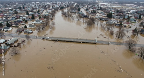 Wide-angle aerial view of a flooded river valley and bridge connecting a submerged town.