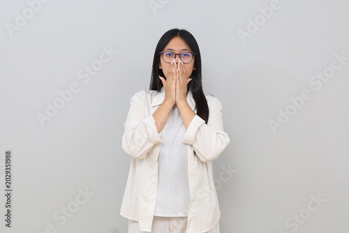 Portrait of a young woman embarrassed covering her mouth with her hand, anxious, experiencing failure, stress, and making mistakes, wearing casual clothes, standing on a white background.