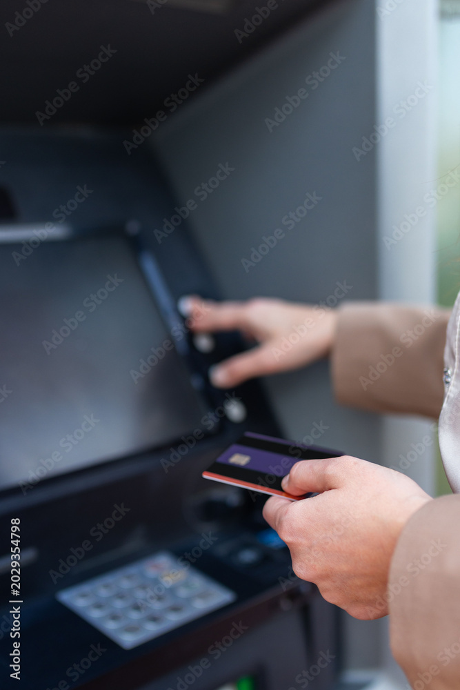 Fototapeta premium Close up of hand inserting bank card into ATM machine, modern banking transaction and financial technology concept