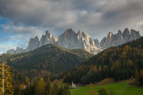 Obraz na płótnie The iconic St Johann Church in Ranui on a green meadow below the Odle mountain peaks in autumn