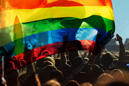Tableau sur toile pride community at a parade with hands raised and the LGBT flag - symbol of love