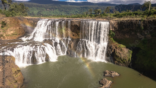 Foto Drone photograph capturing the full width of Sae Pong Lai Waterfall, Laos, with lush green jungle and mountains visible in the background