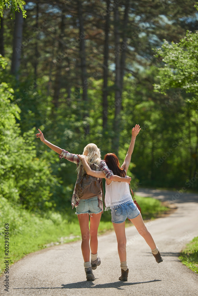 Fototapeta premium Travel, hugging or friends in nature with fun, good time and bonding trip on summer break. Back, sunshine or women in forest with walk, vacation connection or playful embrace in outdoor getaway.