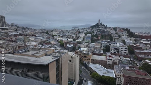 Panoramic time lapse view of the North Beach neighborhood in San Francisco, California, featuring Coit Tower and Telegraph Hill under an overcast sky, with the bay and Alcatraz island in the distance