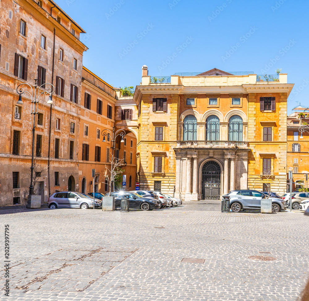 Fototapeta premium Sunny daytime view of an urban square in Rome, Italy, featuring old yellow orange palace facades, an architectural arch bridge street. Italian summer.
