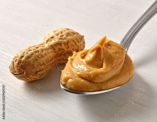 Peanut Butter Spoon with Whole Peanut on White Surface.