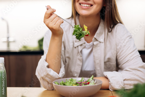 Obraz na plátně Young woman enjoying a vibrant nutritious salad in her modern kitchen, promoting