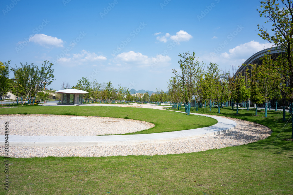 Fototapeta premium Park green space with winding paths under blue sky and white clouds