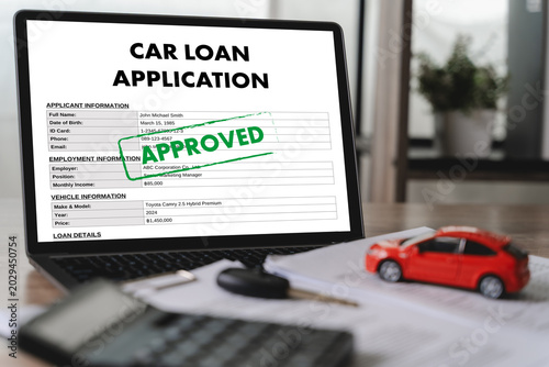 Foto Approved car loan application form displayed on laptop with vehicle model, calculator, car key, and financial documents for online financing, banking approval, and credit verification