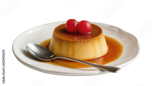 Caramel custard dessert with cherries and spoon on plate