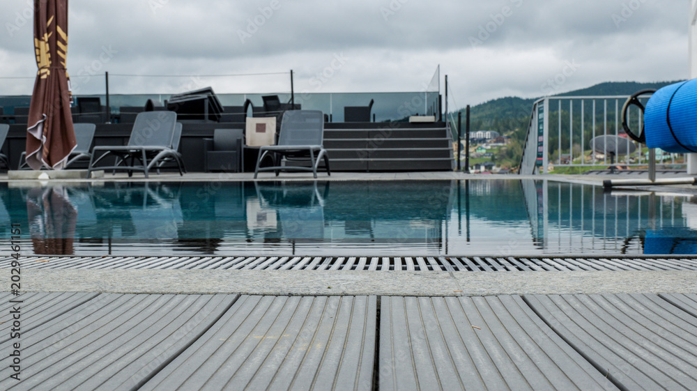 Fototapeta premium Luxury rooftop infinity pool with mountain views on a cloudy day