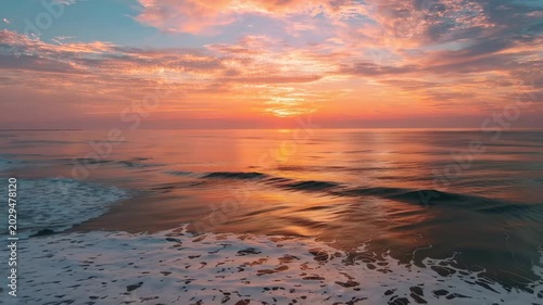 Golden sunrise over ocean waves reflecting warm light on wet sand during dawn cinematic motion