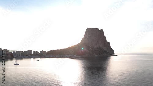 Scenic coastal rock landmark in Calpe, Spain with calm sea and boats nearby.