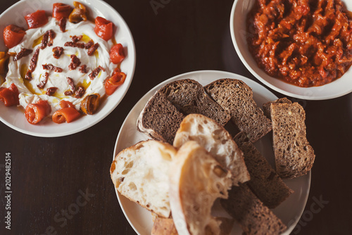 Different types of bread served with tomato dip and yogurt dish at a dining table during a casual meal setting