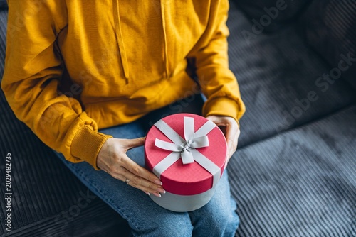 Woman opening gift box with surprise present at home during holiday celebration or special occasion