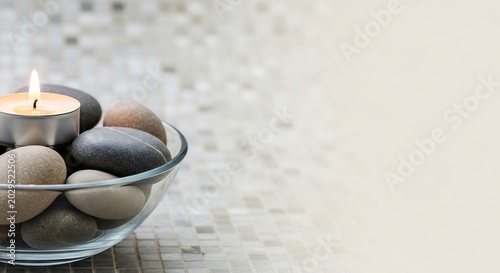 Aromatherapy Candle and Smooth Stones in a Glass Bowl for Spa and Relaxation.