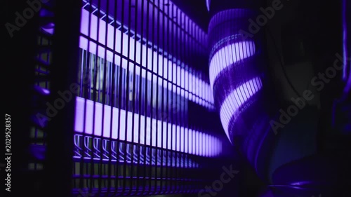 Electric ultraviolet mosquito trap machine with glowing purple tubes inside protective grid designed to attract flying insects and eliminate mosquitoes during warm summer months