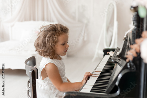 little girl plays the piano at home