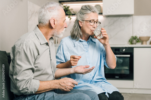 Photos Senior couple at home taking painkiller or prescribed medicine
