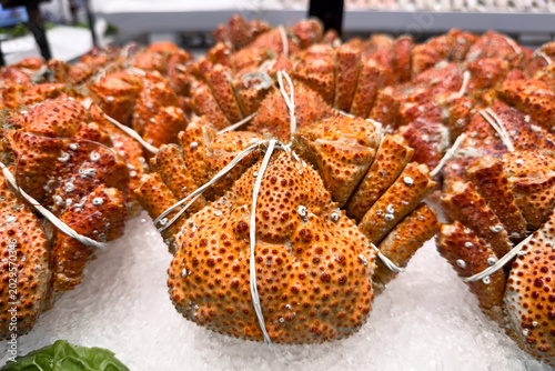 Fotografía Fresh king crab displayed on ice at seafood market counter.