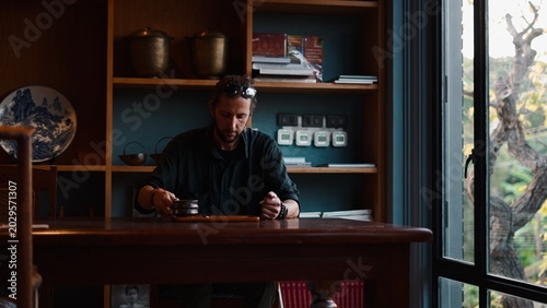 Tableau sur toile Man contemplating while drinking tea, finding calm and focus in a quiet moment