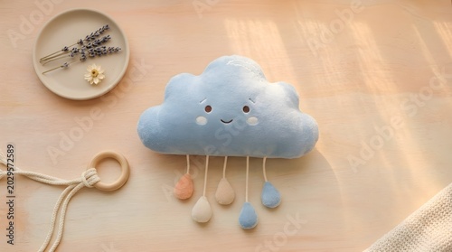 Cloud plush toy with rain droplets hangs on a soft nursery background with a gentle sunlight.