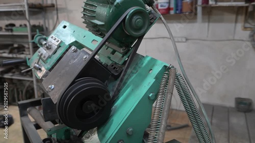 A metal cutting lathe with an electric motor with pulleys and a drive belt. The design of the metal cutting machine in the production room of the workshop