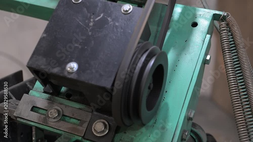 An electric motor with pulleys and a drive belt in the production room of the workshop
