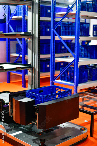 Autonomous robot machine with plastic box in modern industrial warehouse facility.