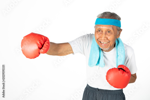 Cheerful elderly Asian man throwing a punch with red boxing gloves isolated on white background
