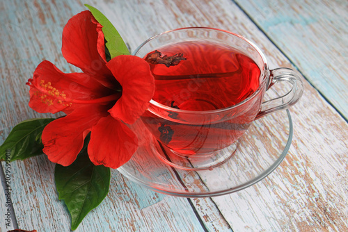 Hibiskus cup of hibiscus tea and hibiscus petals on wooden background