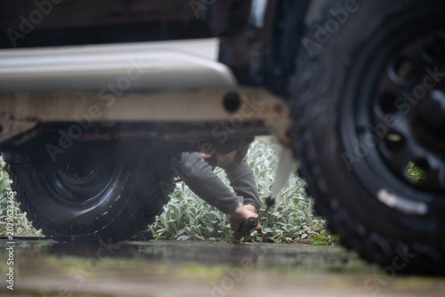 Photos Man washing off-road vehicle undercarriage with pressure washer