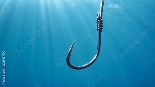 tackle. Underwater close-up of a metallic fish hook in clear blue water. mobility guides, transit brochures, designed for mobility and urban transit guides, clarifies navigation.