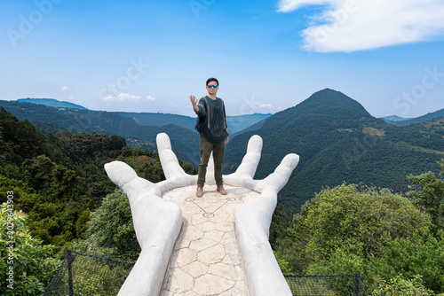 Man standing on giant hand sculpture in zacatlan matliwaka viewpoint