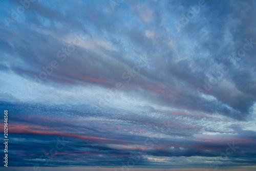 The sky displays a beautiful mix of blue and gray clouds, with horizontal streaks of pink and orange light spreading across the horizon during sunset