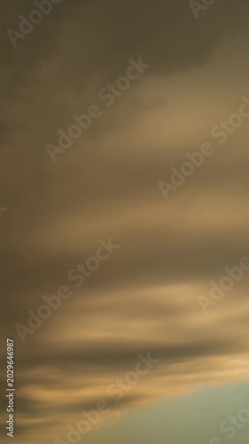 Vertical time lapse of dramatic storm clouds moving fast at sunset.