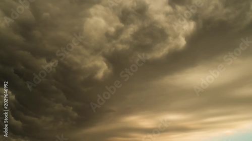 Dramatic time lapse of dark storm clouds moving fast at sunset.