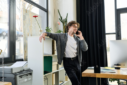 Young man enjoys a phone call while standing in a modern office setting
