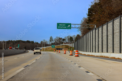 Fotografija Truck vehicles drive on highway near weigh station with construction barriers visible on side