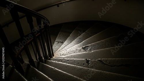 Worn stone spiral staircase in shadow.